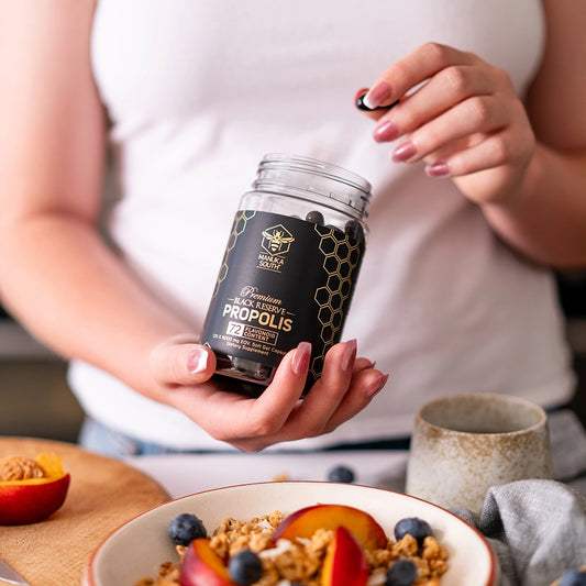 woman holding a propolis capsule in her left hand and the bottle in her right hand