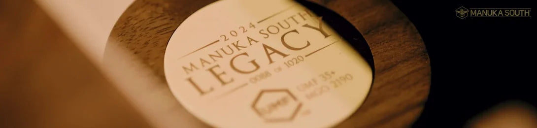 Close-up of a circular Manuka South Legacy 2024 label on a dark wooden surface.