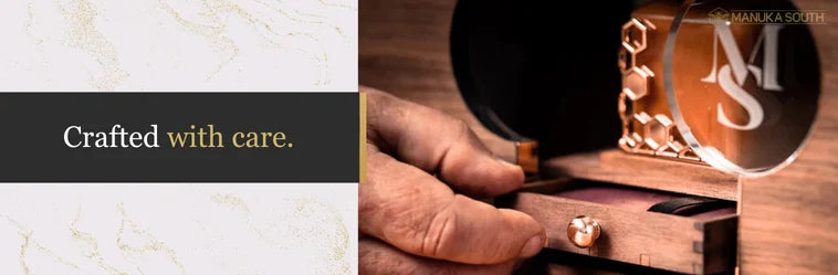 Hand opening a small drawer of a meticulously crafted wooden box, revealing a honey product.