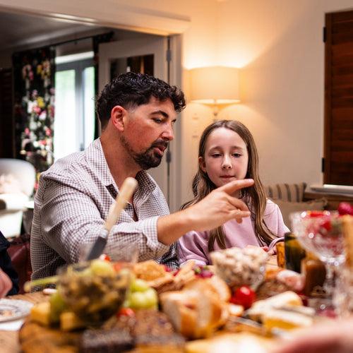 Man and young girl at a dining table with food