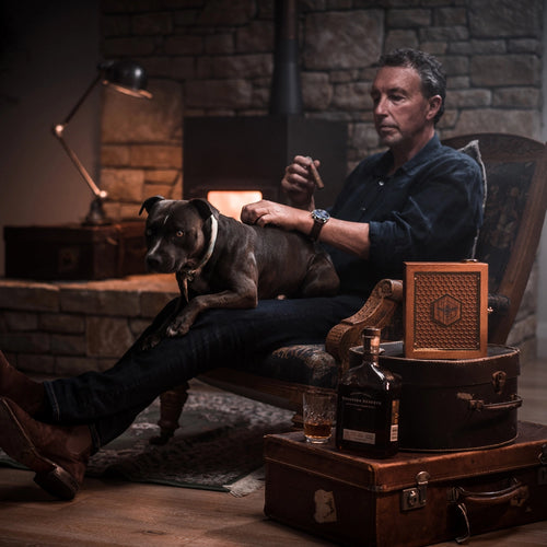 man with his dog; manuka honey and whiskey on top of boxes beside the man