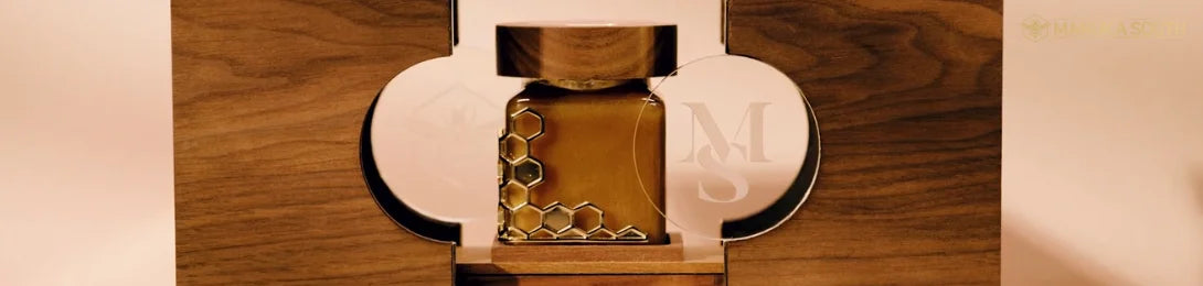 Gold-colored hexagonal patterned jar, possibly containing premium Manuka honey, in a wooden box.